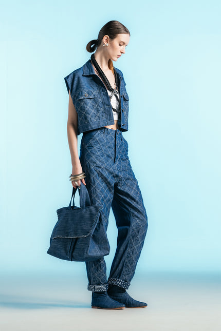 Model wearing Nena Jacket in cotton denim, featuring a cropped sleeveless silhouette and diamond-patch textured detailing.