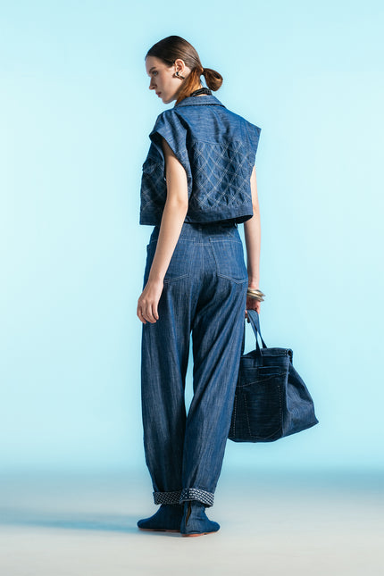 Model wearing Nena Jacket in cotton denim, featuring a cropped sleeveless silhouette and diamond-patch textured detailing.