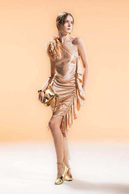 Model wearing a one-shoulder silk dress with adjustable shoulder tie and side drawstring detail, creating a slim silhouette.