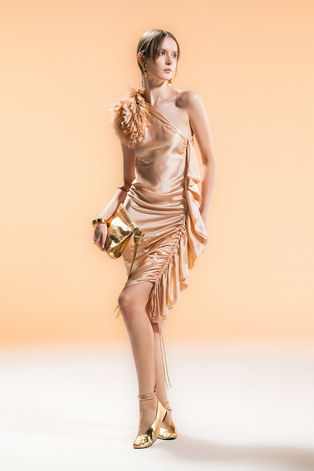 Model wearing a one-shoulder silk dress with adjustable shoulder tie and side drawstring detail, creating a slim silhouette.