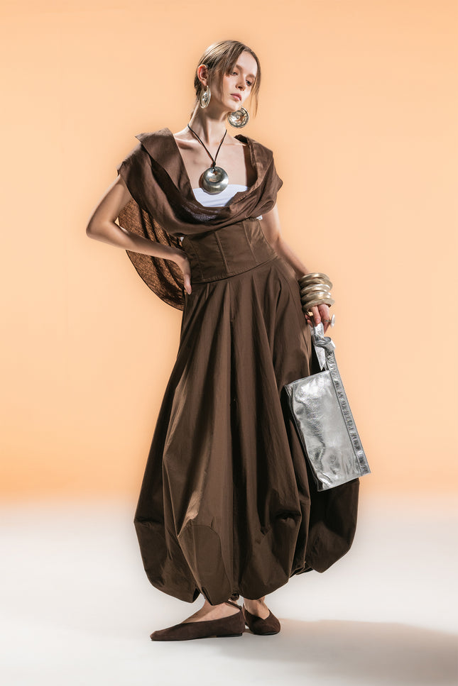 Model wearing a sleeveless cape with draped cowl neckline, creating soft folds and an airy silhouette.