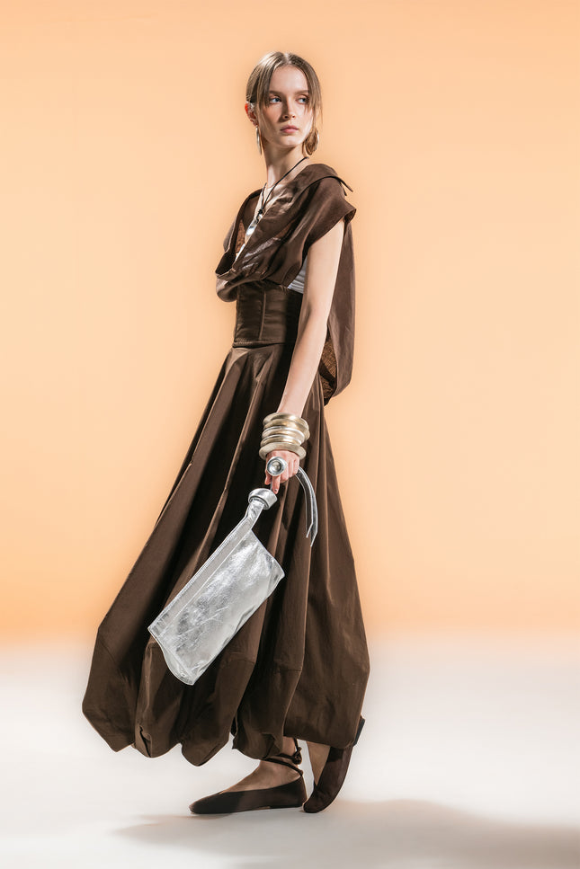 Model wearing a sleeveless cape with draped cowl neckline, creating soft folds and an airy silhouette.