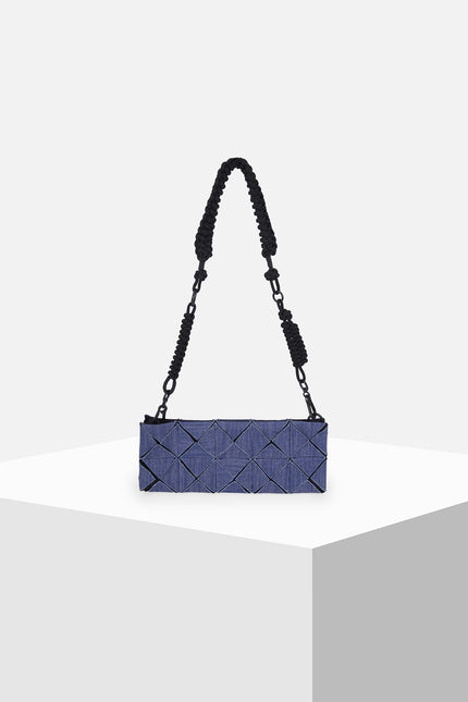 Model carrying the Oleander cotton clutch with an all-over geometric pleated texture and detachable knotted strap.