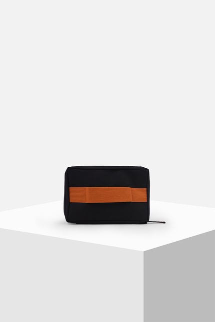 Canvas pouch with bold tarpaulin stripe appliqué, zipper closure, contrast handle, and internal mesh pocket.