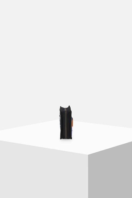 Canvas clutch featuring zebra tarpaulin appliqué, zipper closure, contrast handle, and internal mesh pocket.