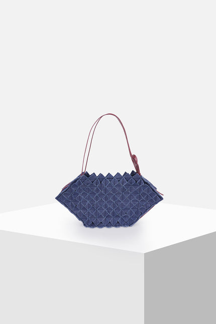 Olympie bag with a hexagonal shape, all-over geometric origami folds, magnetic closure, adjustable leather shoulder strap, and knotted side detail.