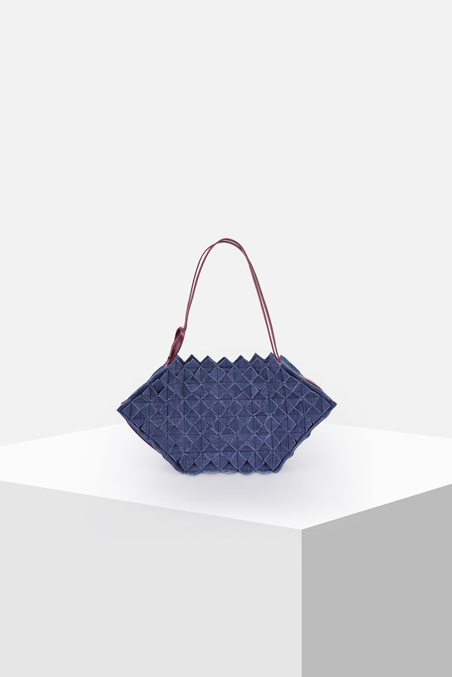 Olympie bag with a hexagonal shape, all-over geometric origami folds, magnetic closure, adjustable leather shoulder strap, and knotted side detail.